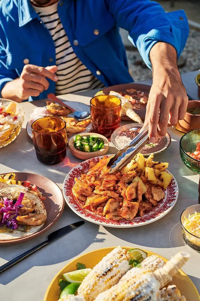 Outdoor Mexican-style spread with shredded chicken, tacos and elote