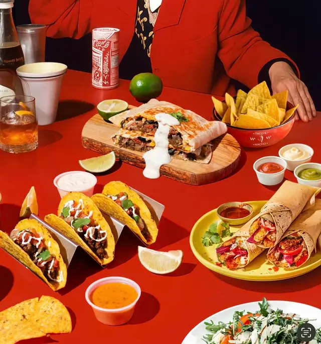 Vibrant Mexican spread: tacos, burrito, nachos on red tabletop