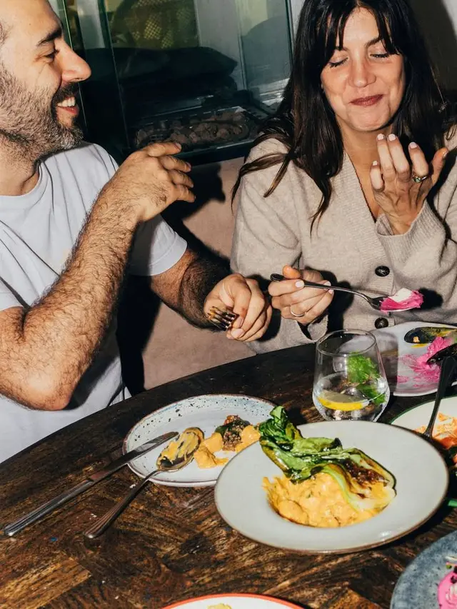 Couple tasting dishes at a rustic restaurant table
