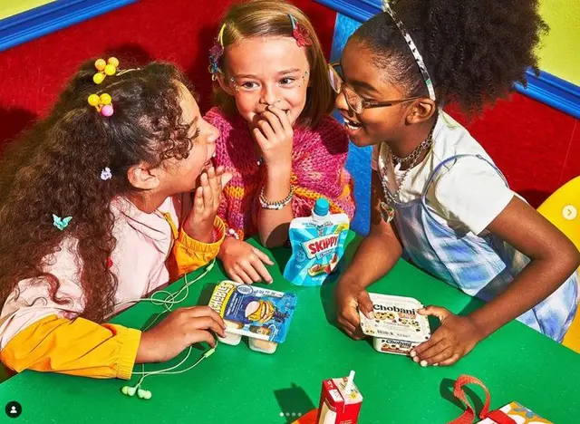 Kids sharing snacks at colorful play table with Chobani and Skippy