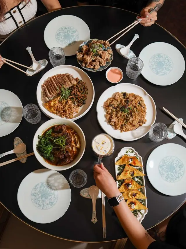 Overhead family-style Asian dinner on round black table