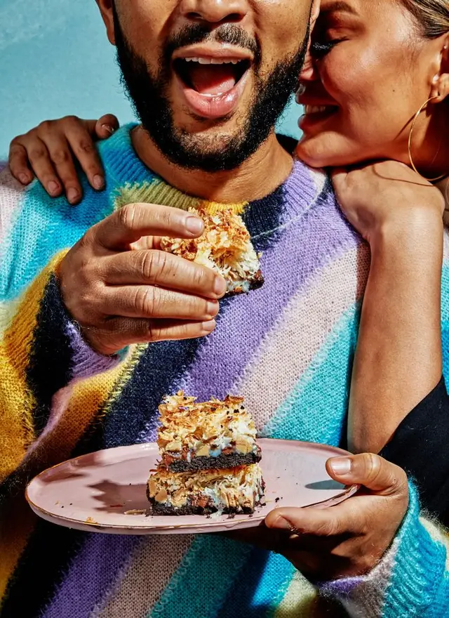 Couple sharing toasted coconut chocolate bars on pink plate, colorful striped sweater