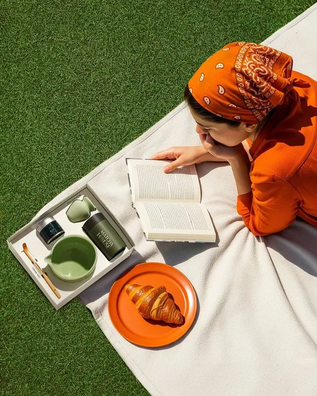 Outdoor matcha breakfast — orange bandana, croissant and open book