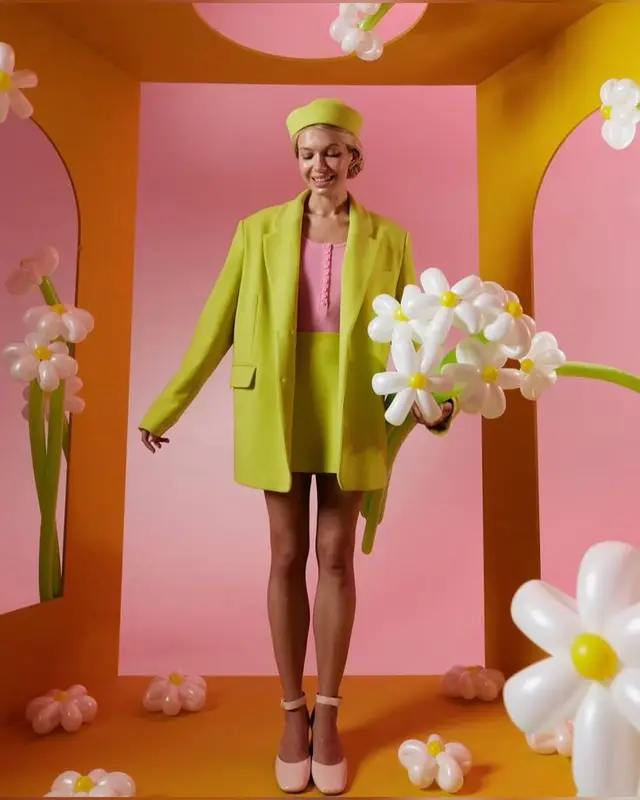 Lime green blazer and mini skirt with balloon daisy bouquet on pink-orange studio set