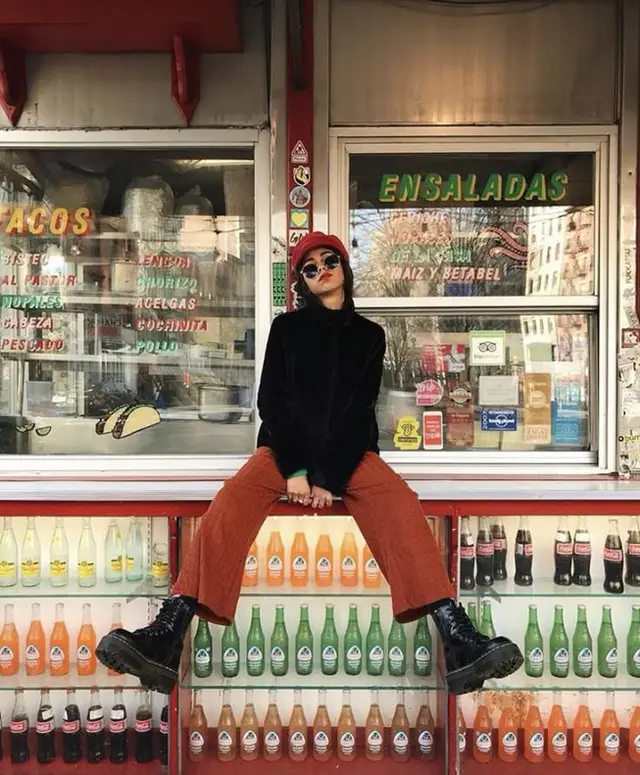 Street-style portrait at Mexican taquería window with rows of glass soda bottles