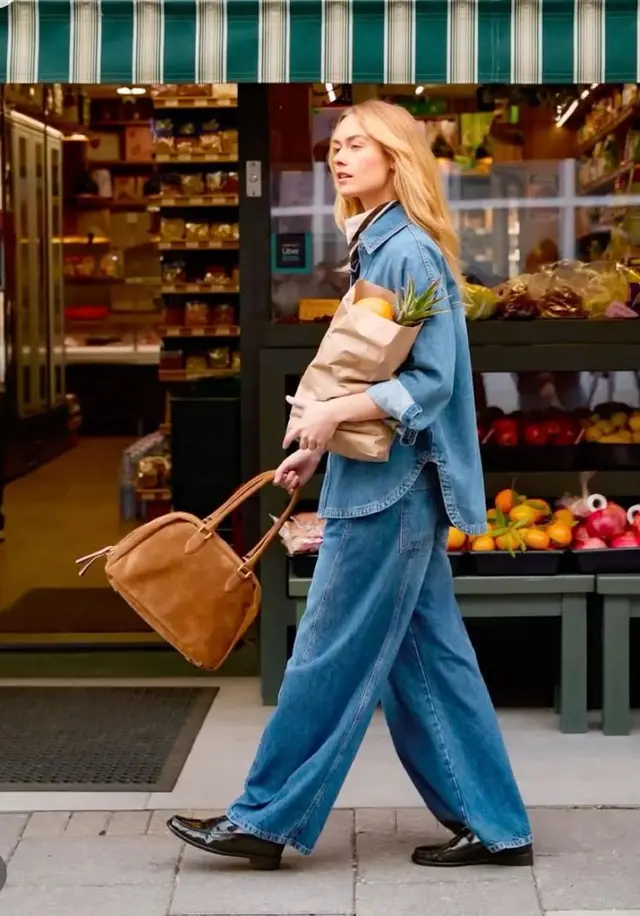 Denim-on-denim look with suede bag outside neighborhood produce shop