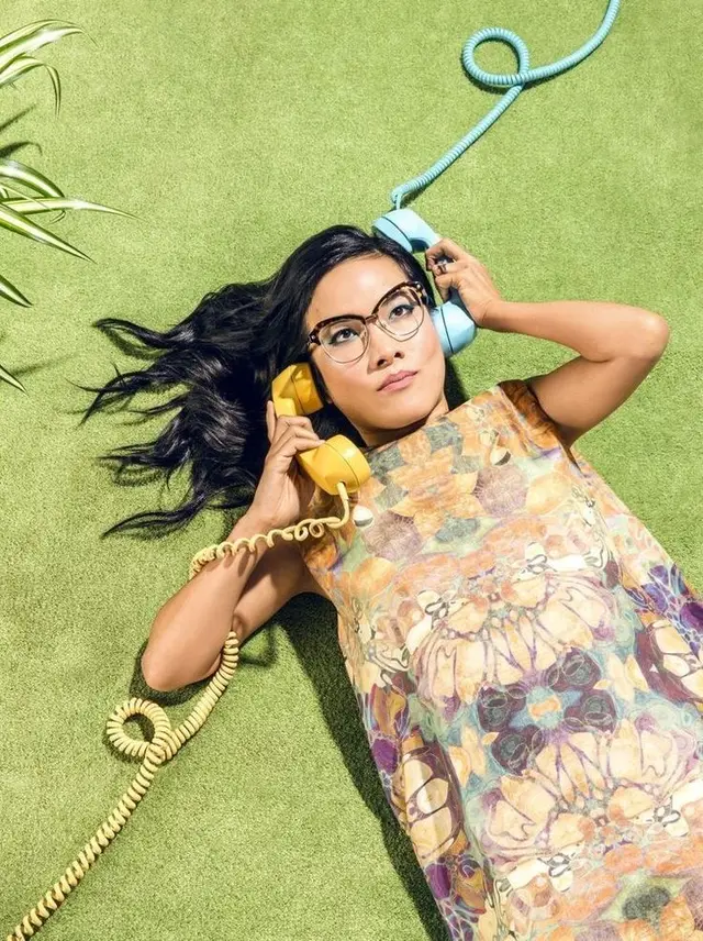 Woman on Green Turf Holding Yellow and Blue Corded Telephones