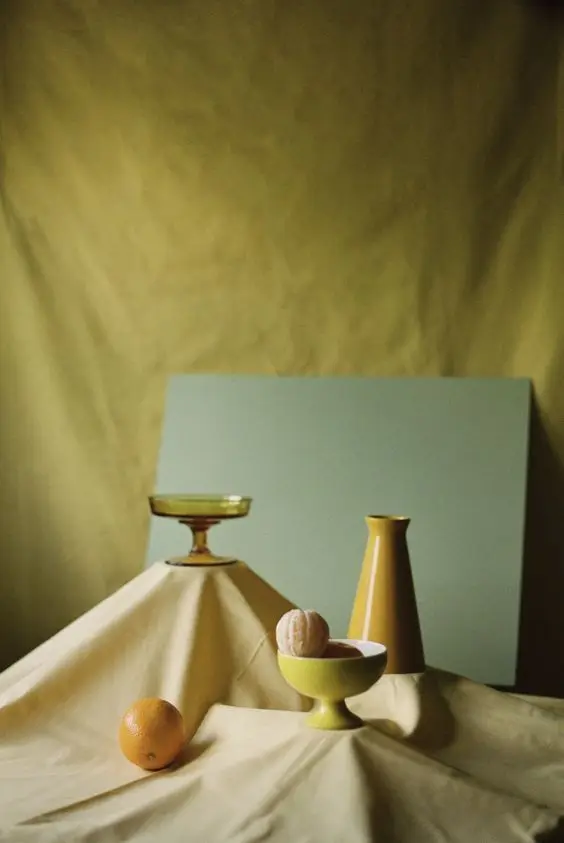 Mustard-yellow ceramics and citrus still life with olive backdrop