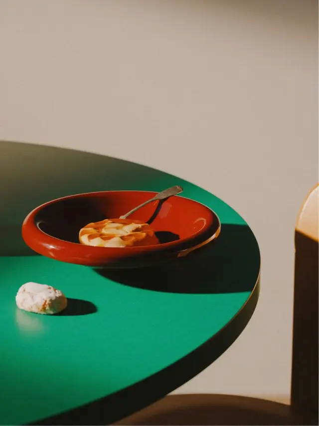 Red ceramic bowl with pastry on teal round table