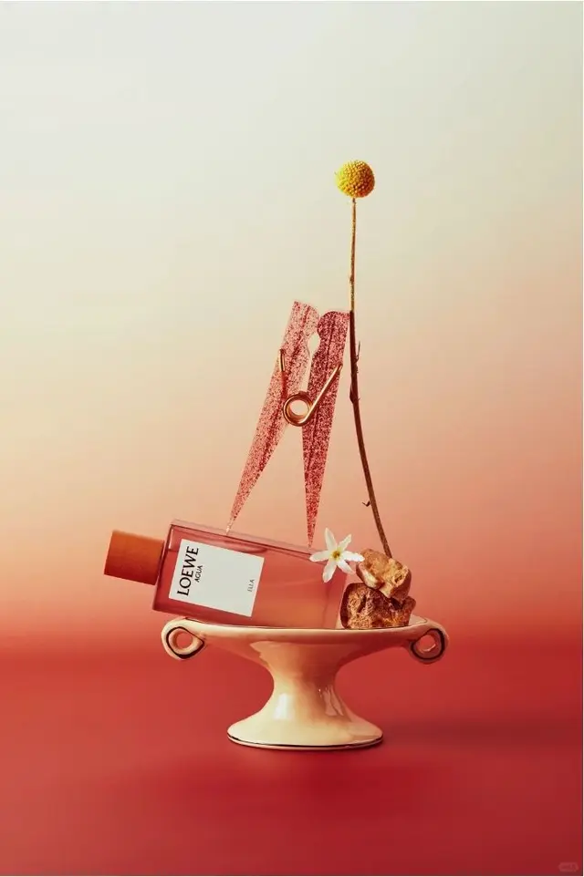 LOEWE perfume still life on ceramic pedestal with craspedia and glitter clothespin