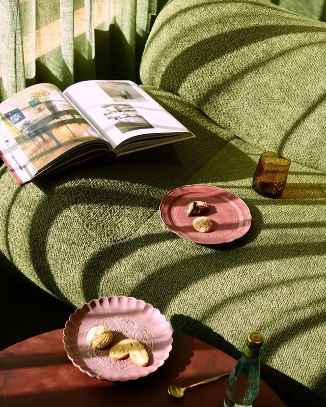 Olive boucle sofa vignette with dusty-rose scalloped plates and open design magazine