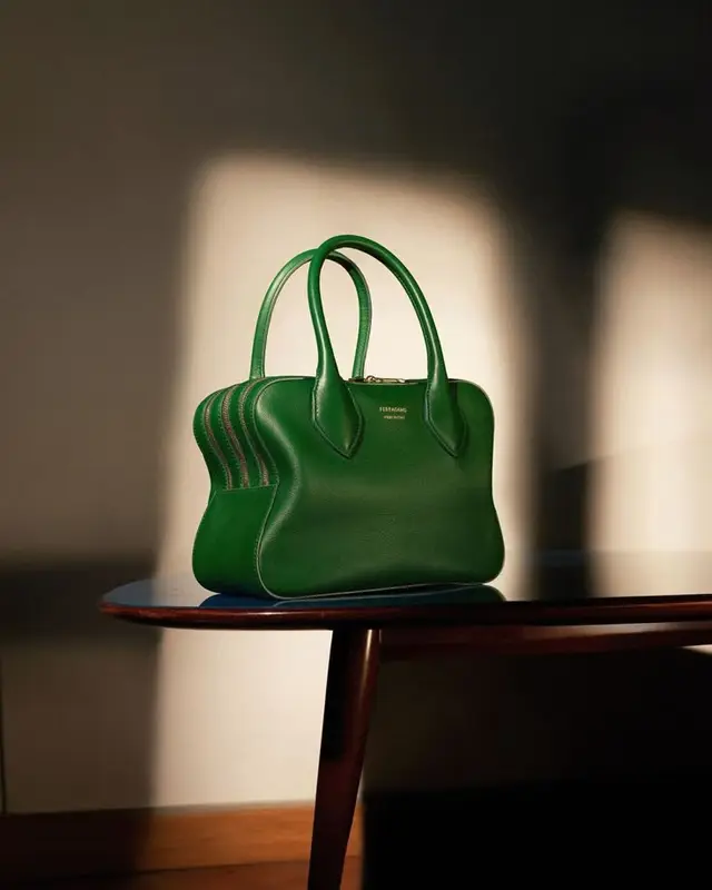 Emerald green Ferragamo leather handbag on wooden table