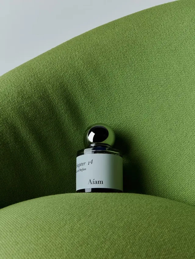 Chapter 14 (Aíam) perfume bottle on lime-green upholstered cushion