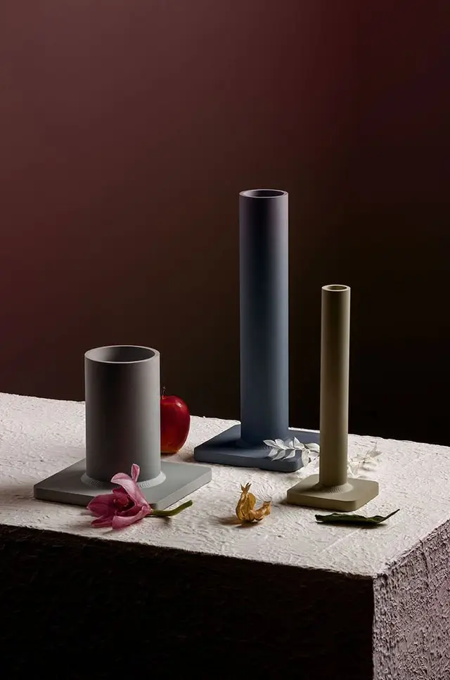 Minimalist matte ceramic cylinder vessels on plaster pedestal