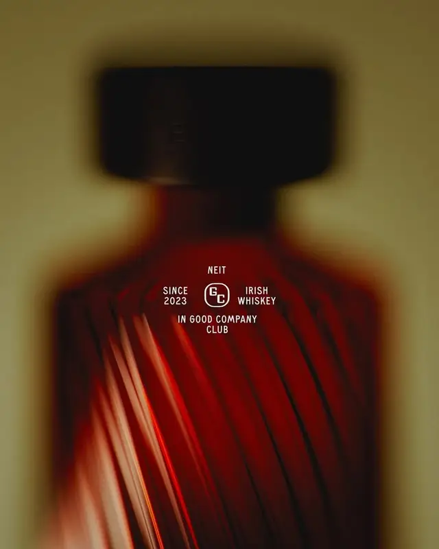 Close-up ribbed amber Irish whiskey bottle with 'In Good Company Club' logo