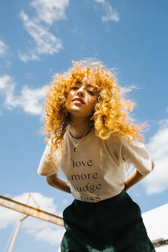 Low-angle portrait of woman with golden curls and slogan tee