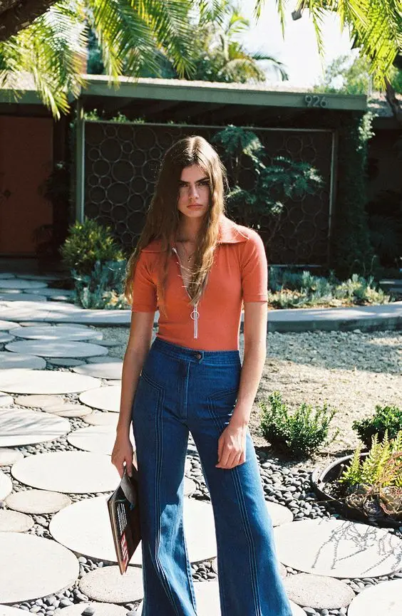 Rust zip-polo and high-waist wide-leg jeans — sunlit mid-century front yard