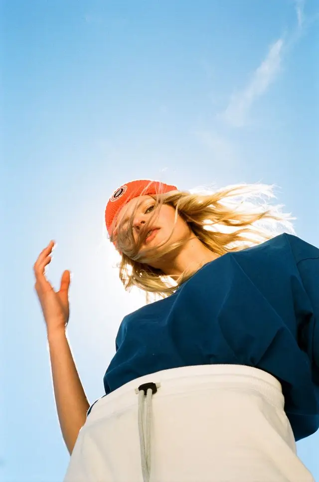 Low-angle backlit portrait with orange beanie and blue sweatshirt