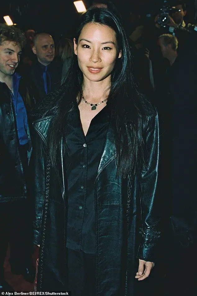 Woman in black leather trench coat and padlock necklace at photographers' event