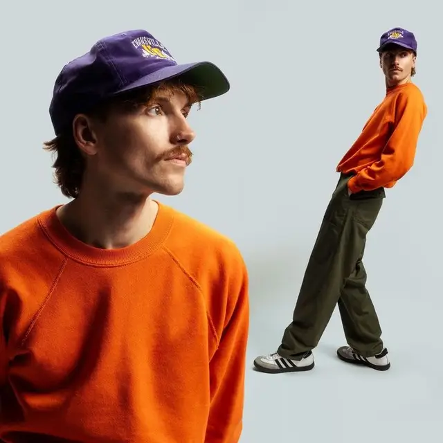 Orange crewneck and purple cap — studio streetwear portrait
