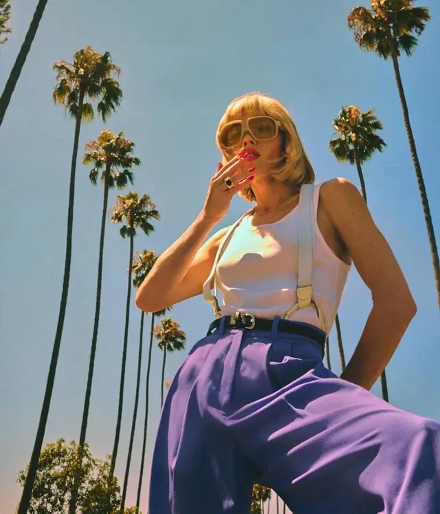 Retro summer portrait — white tank, suspenders and purple high-waist trousers under palm t