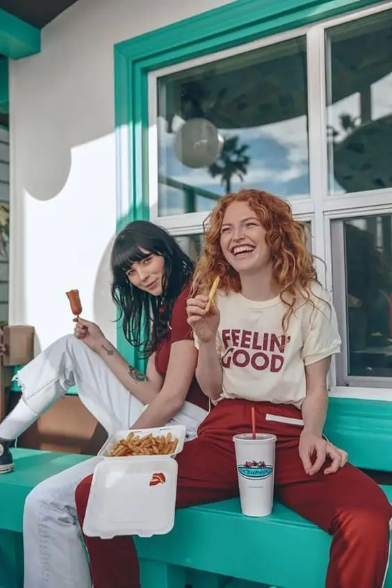 Two friends eating fries at a turquoise retro diner window
