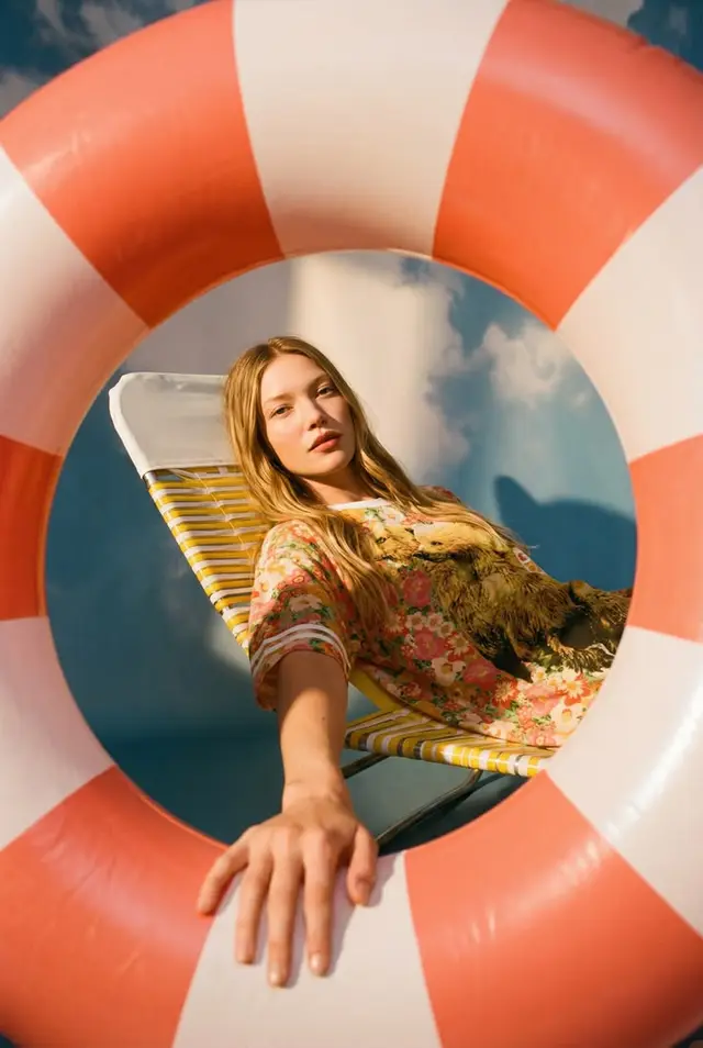 Summer editorial portrait through a coral-and-white lifebuoy