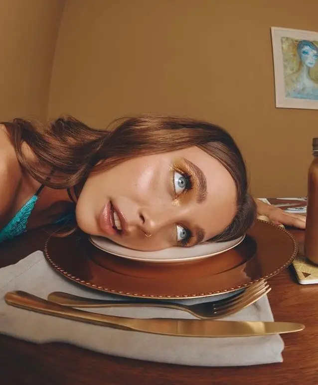 Surreal editorial: woman's head on a copper charger with gold flatware