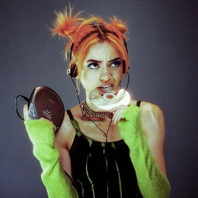 Portrait with orange space‑buns biting a CD while holding a Discman