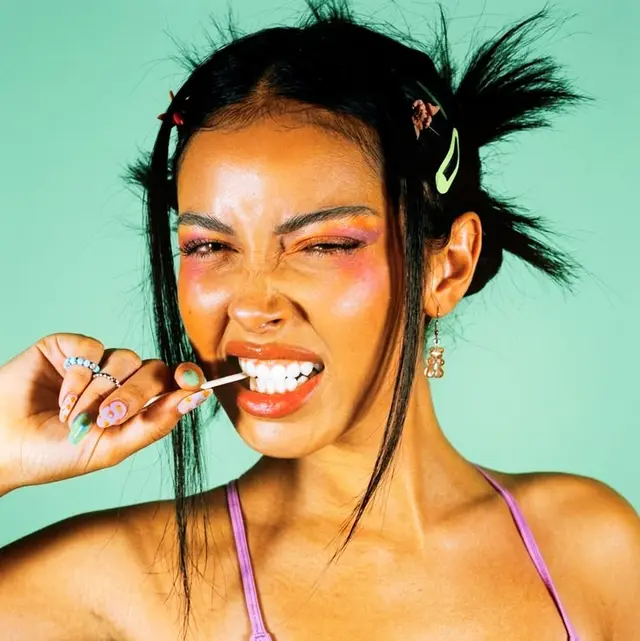 Studio portrait — woman biting white lollipop stick, mint background