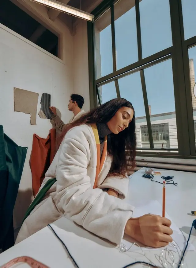 Sunlit fashion studio — designer sketching at worktable