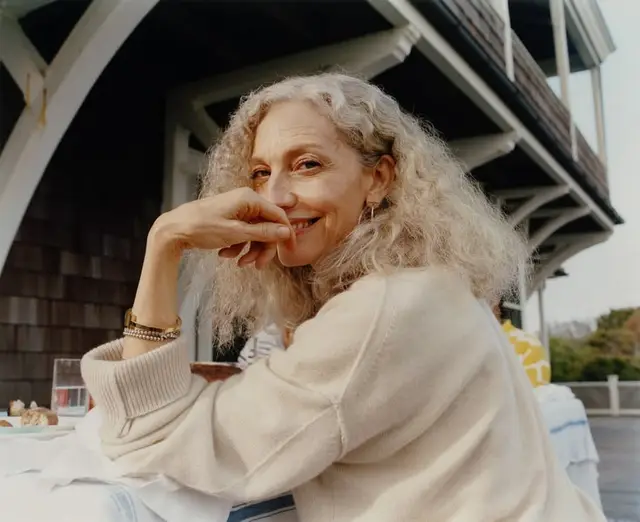 Candid coastal portrait — woman in cream knit sweater on porch breakfast