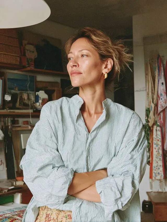 Casual portrait: oversized striped cotton shirt in a textile-filled home studio