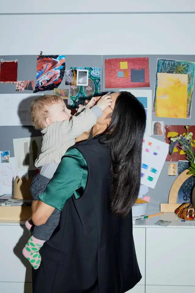 Parent holding toddler in front of art-filled inspiration wall