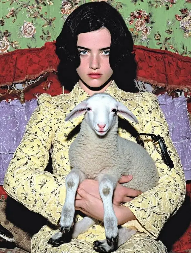 Young woman in yellow brocade dress holding a white lamb — fashion editorial portrait