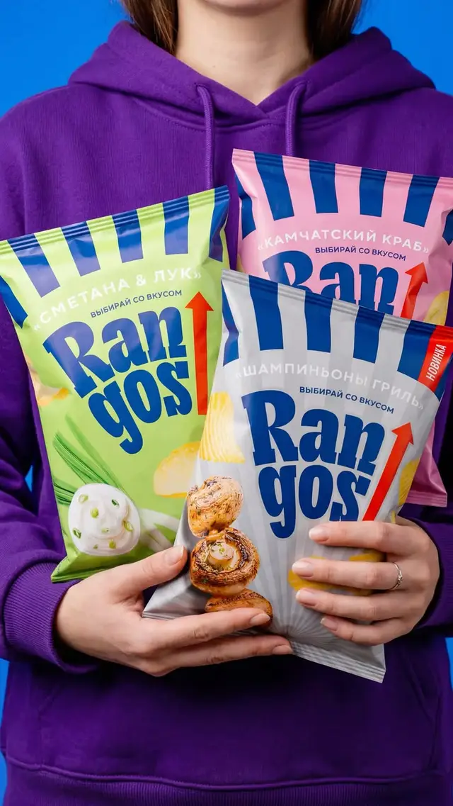 Rangos snack chip packaging — three flavor bags held against purple hoodie