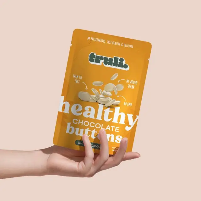truli. healthy white chocolate buttons — mustard-yellow resealable pouch product shot