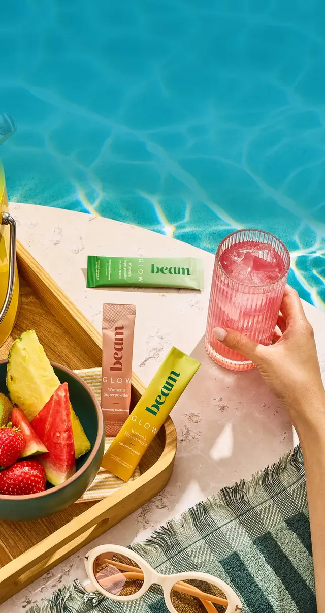 Poolside still: Beam Glow sachets with fruit bowl and pink drink