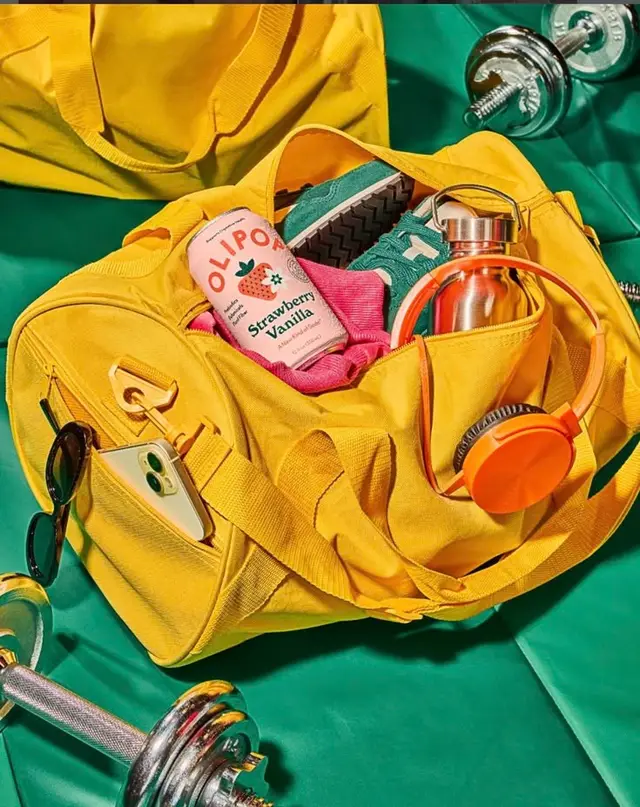 Yellow canvas gym duffel with Olipop can and workout gear