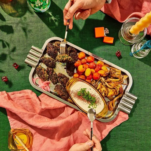 Stainless serving tray mezze with meatballs, cherry tomatoes, mushrooms and creamy dip