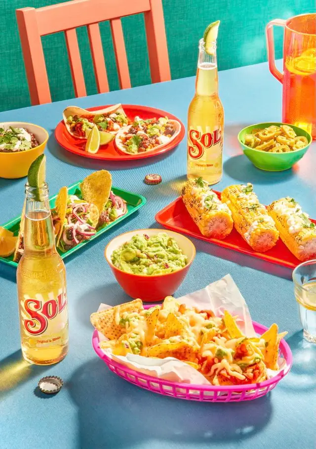 Sol beer with colorful Mexican street-food spread on turquoise table