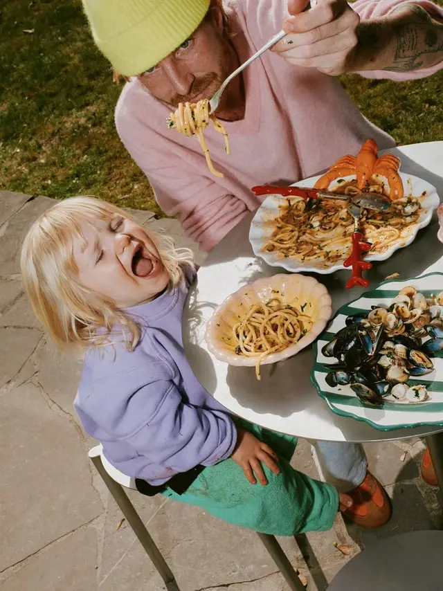 Outdoor seafood pasta — candid moment with child and adult
