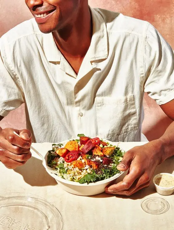 Roasted vegetable grain bowl held by model in white shirt — Pinterest food styling