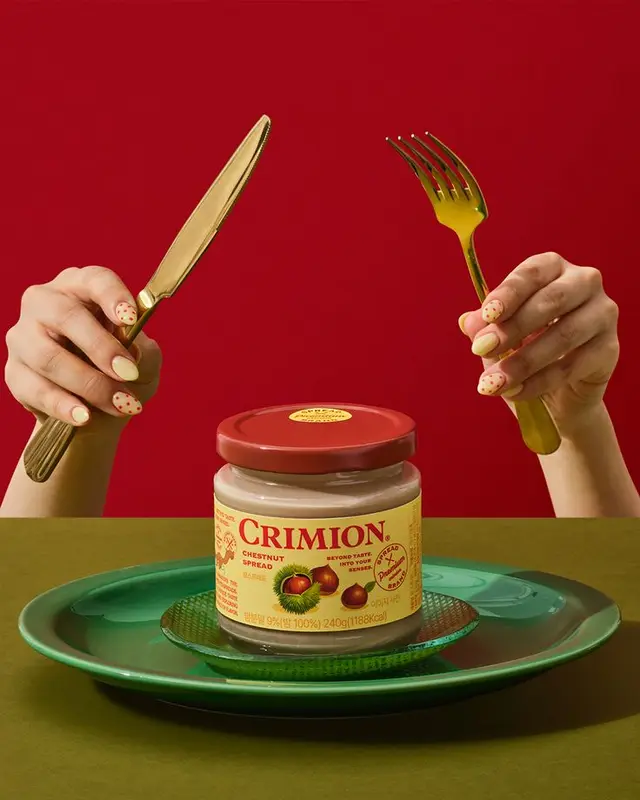 Crimion Chestnut Spread jar with gold cutlery on green plate, red backdrop