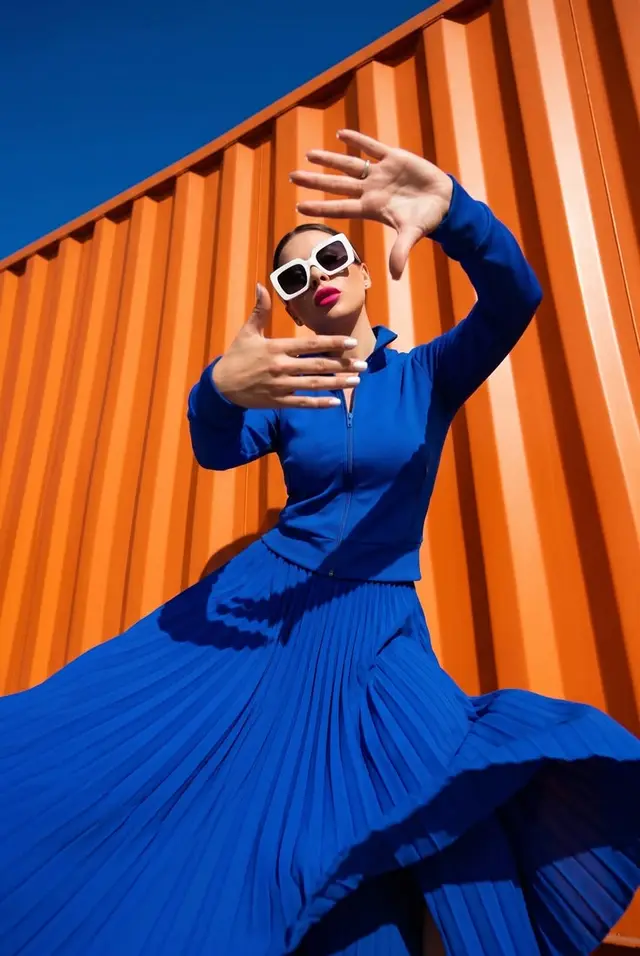 Cobalt blue pleated skirt against orange shipping container