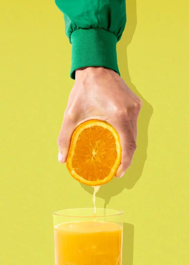 Hand Squeezing Orange into Glass — Bright Minimal Food Photo