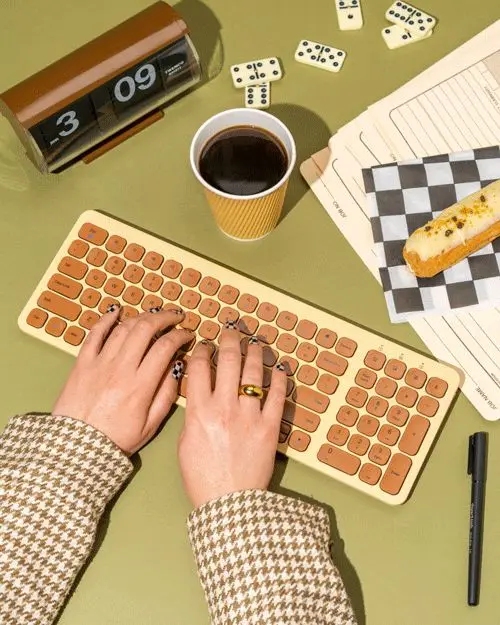 Retro tan keyboard flat-lay with coffee, pastry and flip clock