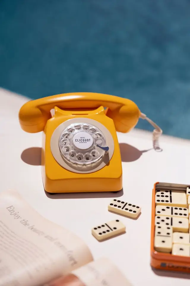 Mustard-yellow rotary phone with dominoes at poolside