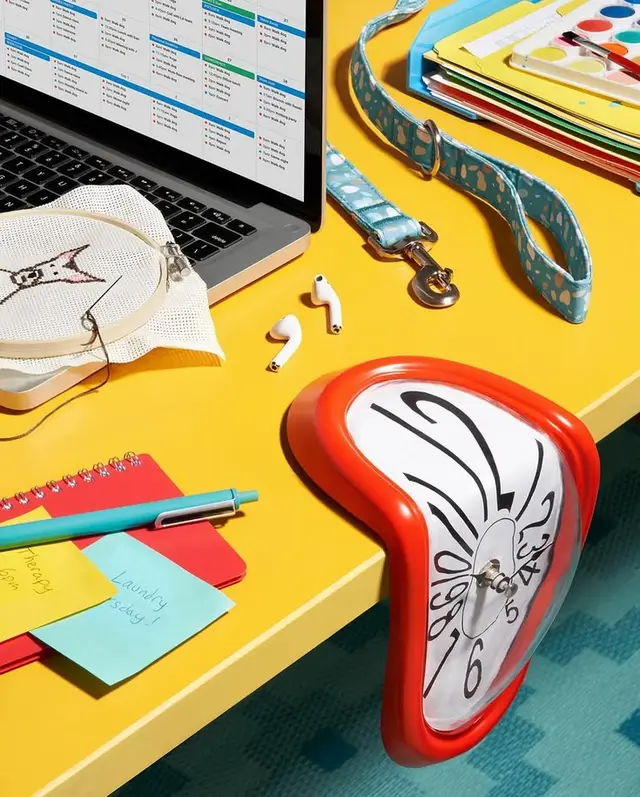 Bright yellow desk still life with melting clock and craft supplies