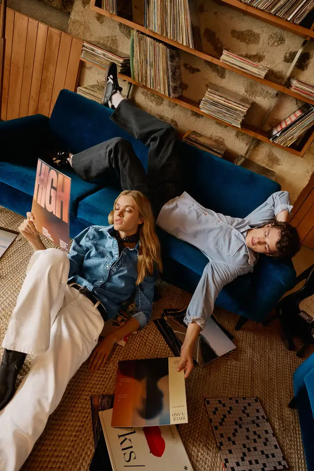 Couple lounging with vinyl records on blue velvet sofa in retro living room